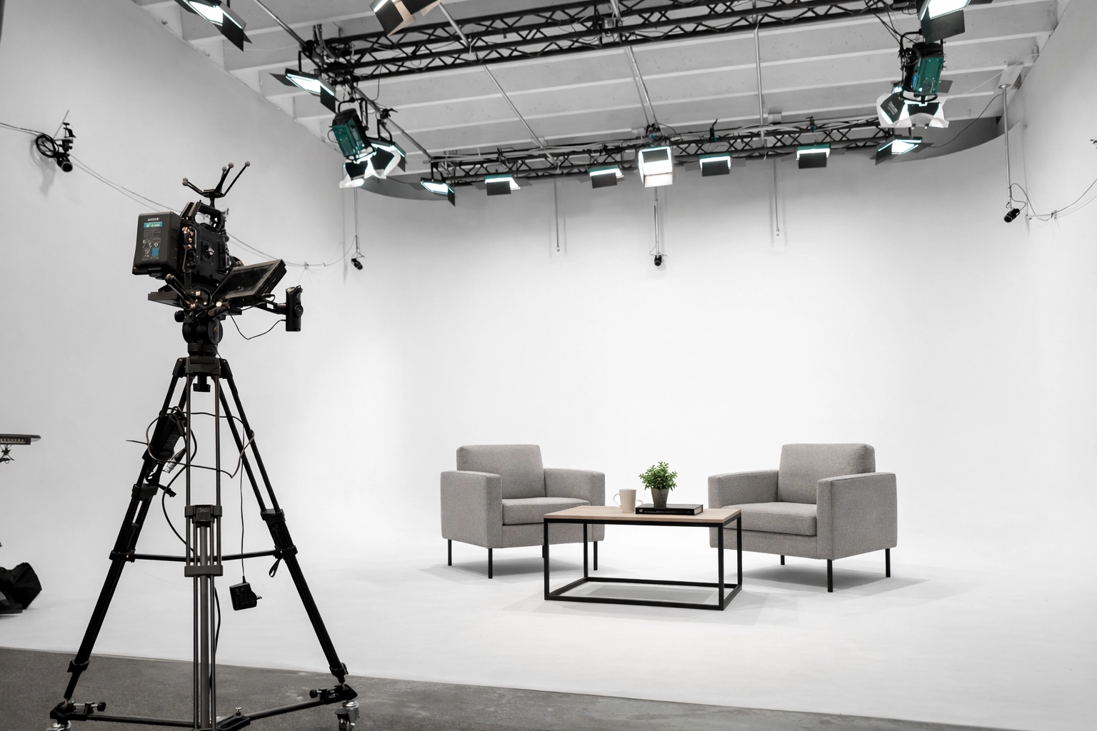 Interview set in a Miami production studio with two chairs, a coffee table, professional lighting, and camera equipment