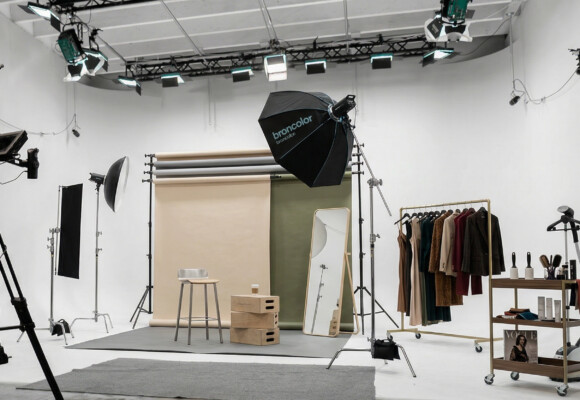 Fashion editorial photography set in a Miami production studio with backdrops, lighting, styling rack, and makeup station
